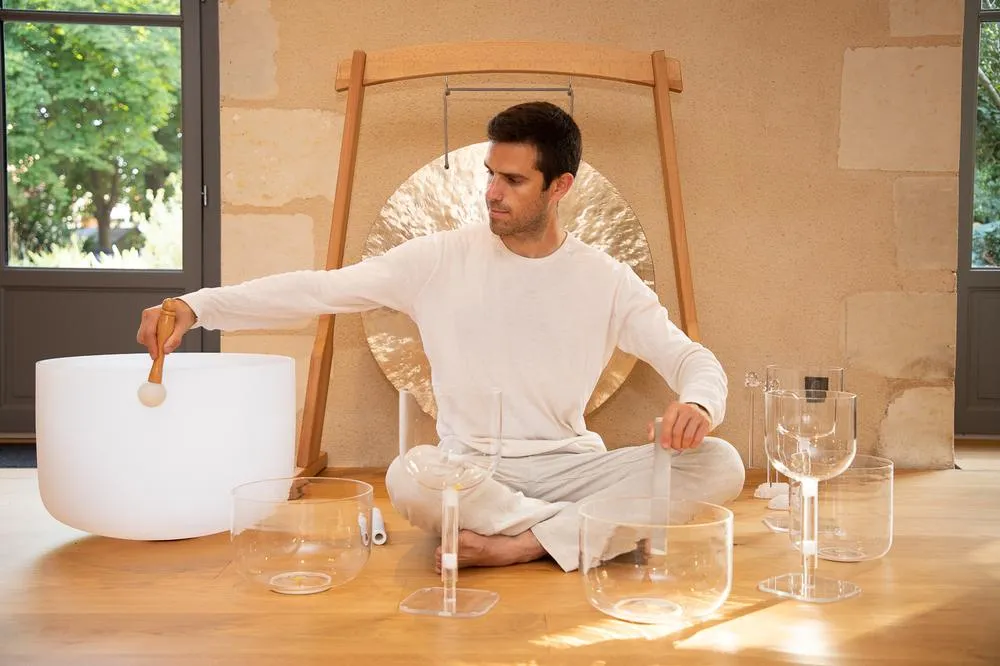 Alexandre Tonnelier assis en tailleur au milieu de bols chantants en cristal