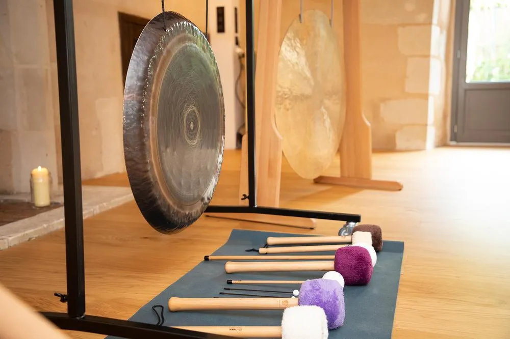 Deux gongs sur leurs supports et une série de mailloches alignées sur un tapis