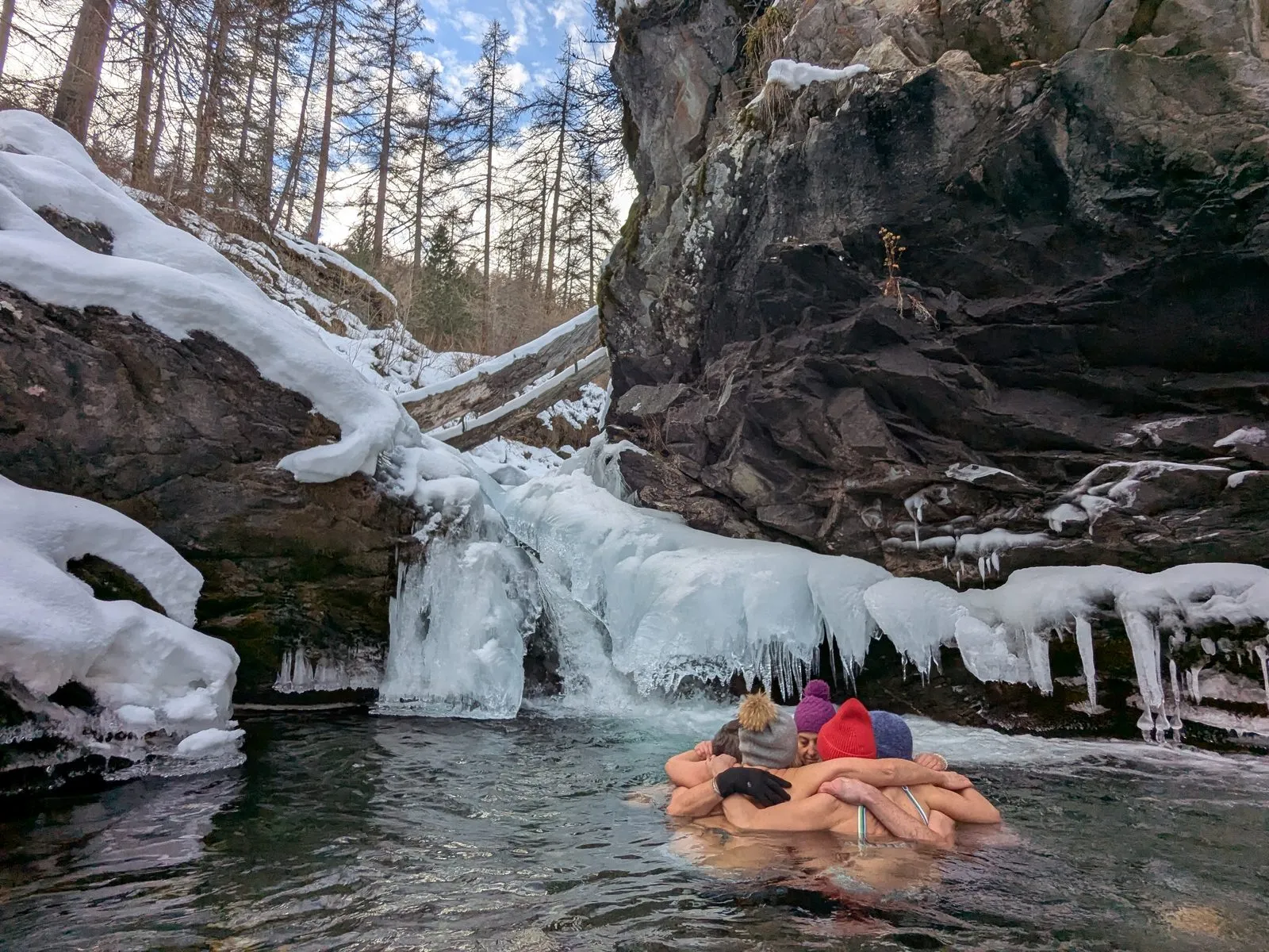 Groupe enlacé dans une vasque d'eau glacée au pied d'une cascade gelée